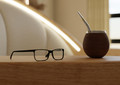 Closeup of reading glasses and a yerba mate gourd on the arms of the chair